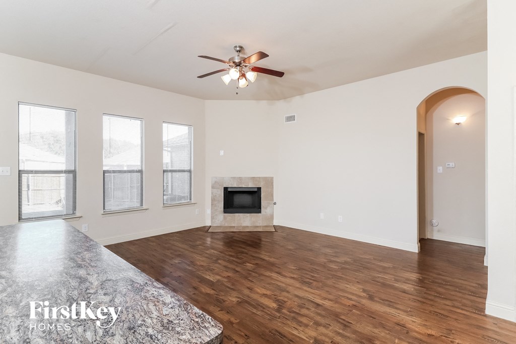 A spacious living room with a fireplace and a ceiling fan.