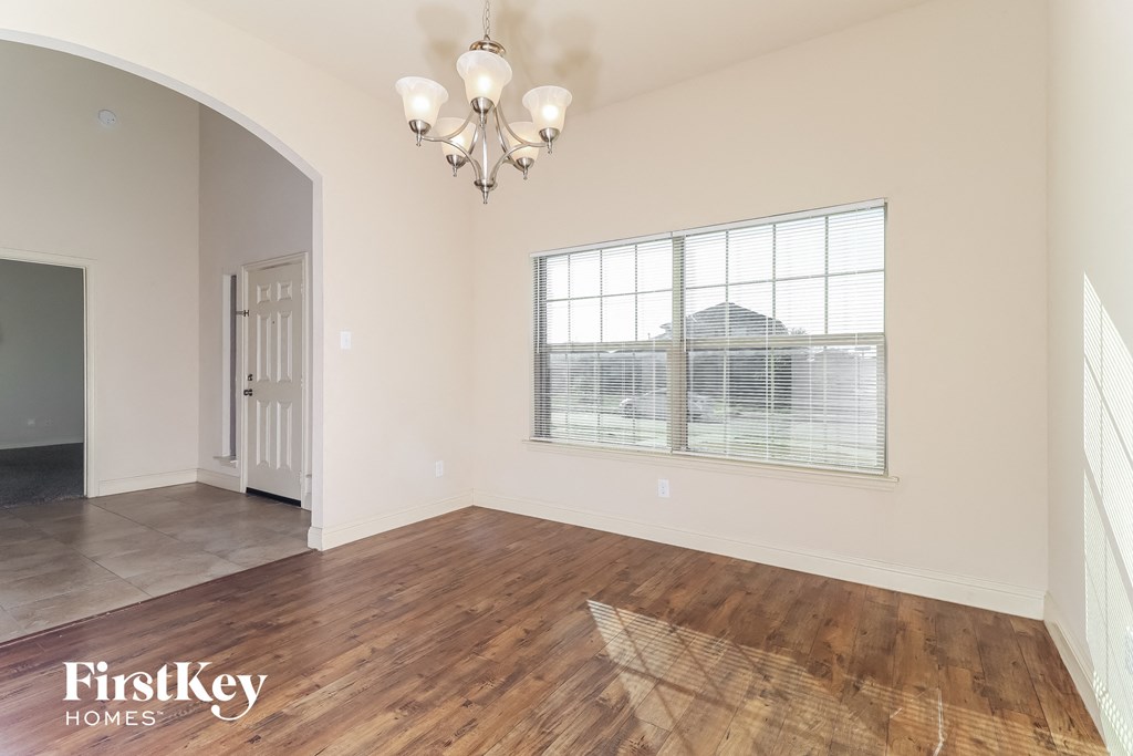 A room with wooden floors and a chandelier is shown.