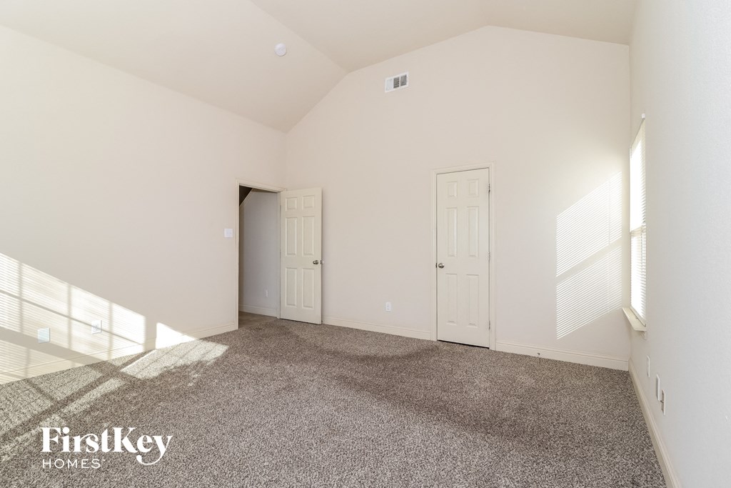 A sparsely furnished room with a carpeted floor and white walls.
