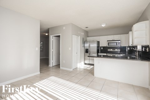 A kitchen with a black counter top and white cabinets.