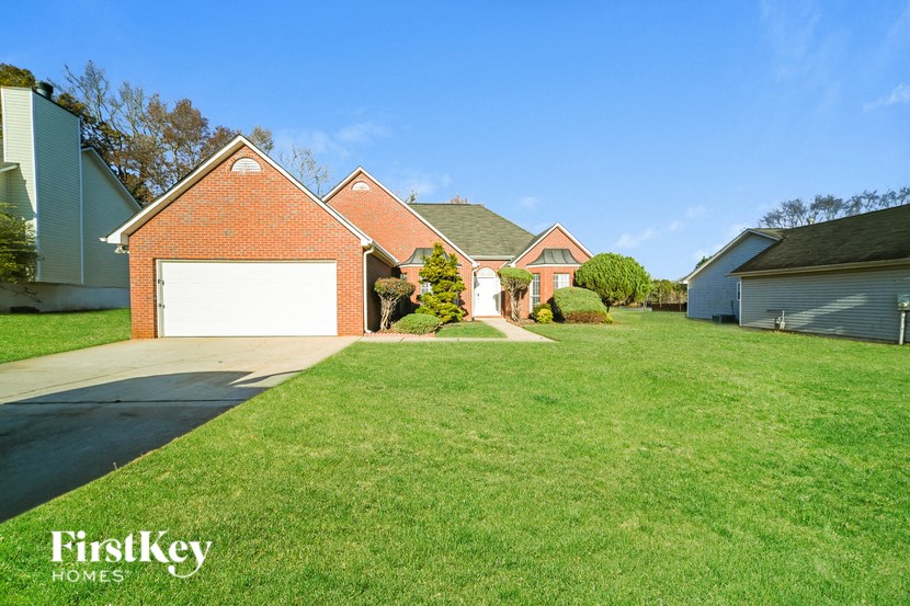 A house with a red brick facade and a white garage door is for sale.