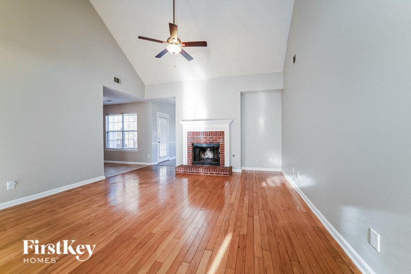 A spacious room with a fireplace and wood flooring.