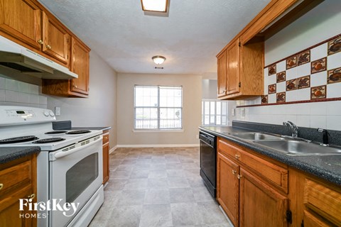 A kitchen with wooden cabinets and a white stove top oven.