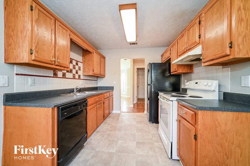 A kitchen with wooden cabinets and black countertops.