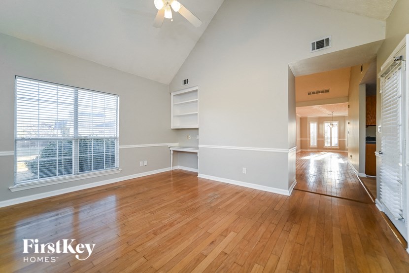 A spacious room with wooden floors and a large window.