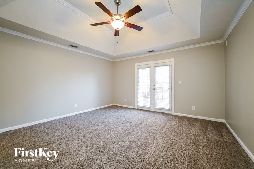 A room with a ceiling fan and carpeted floor.
