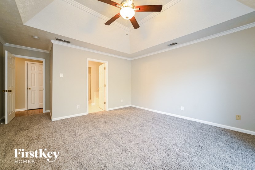 A spacious room with a ceiling fan and carpeted floor.