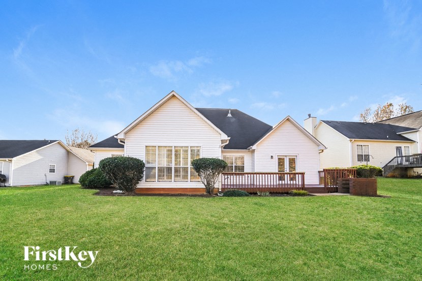 A white house with a black roof is surrounded by other similar houses.