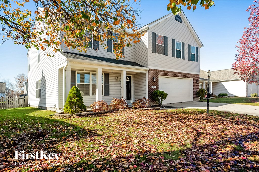 a white house with a yard with autumn leaves on the ground