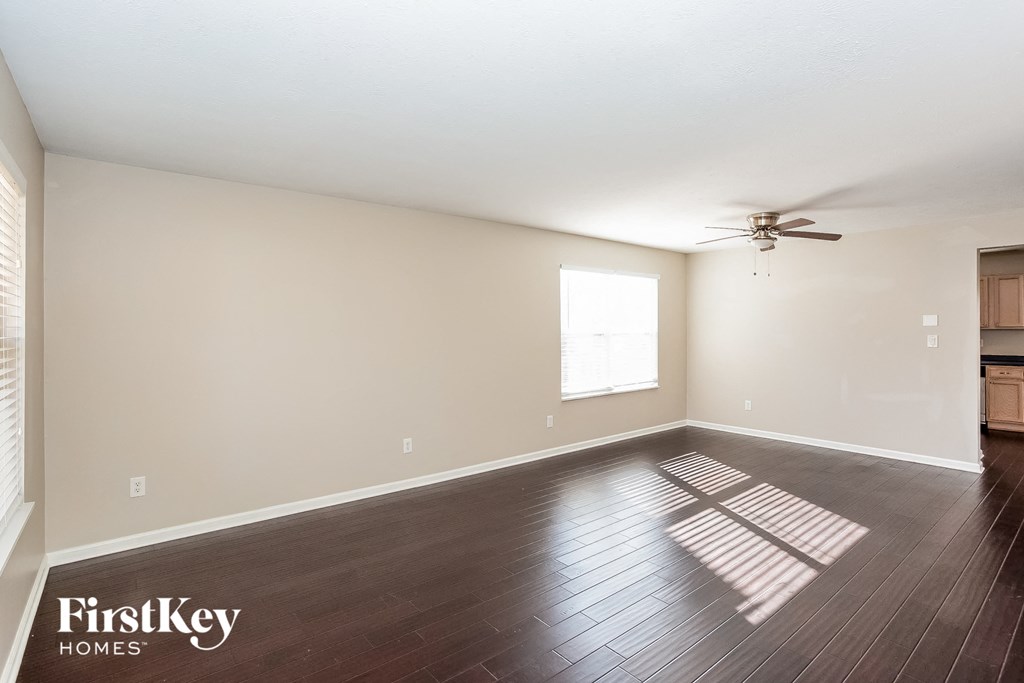 an empty living room with wood floors and a ceiling fan