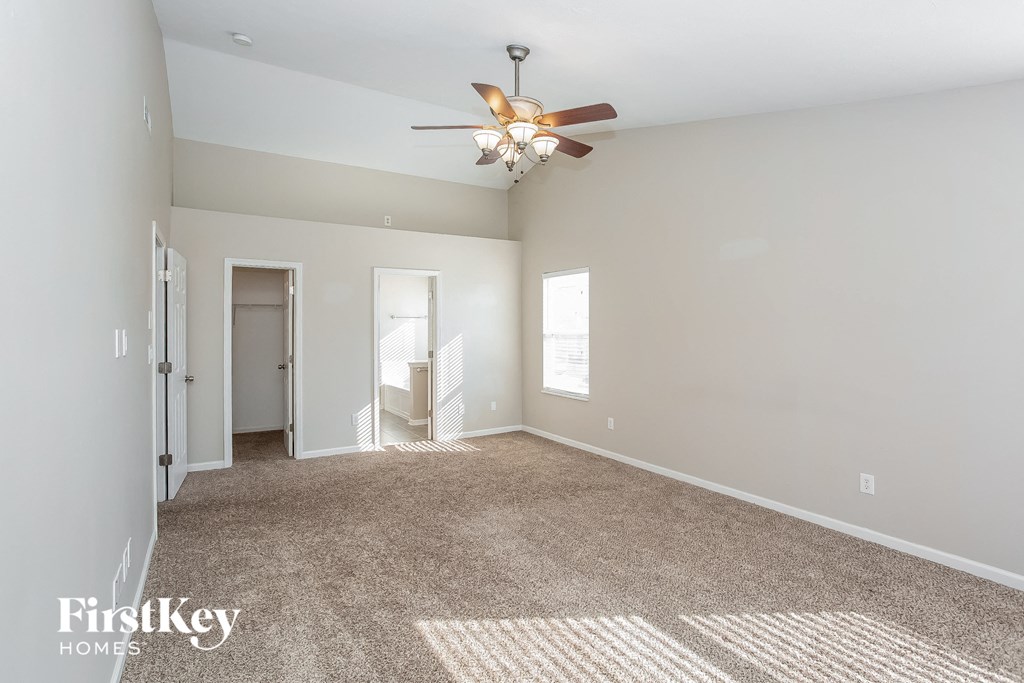 a spacious living room with carpet and a ceiling fan