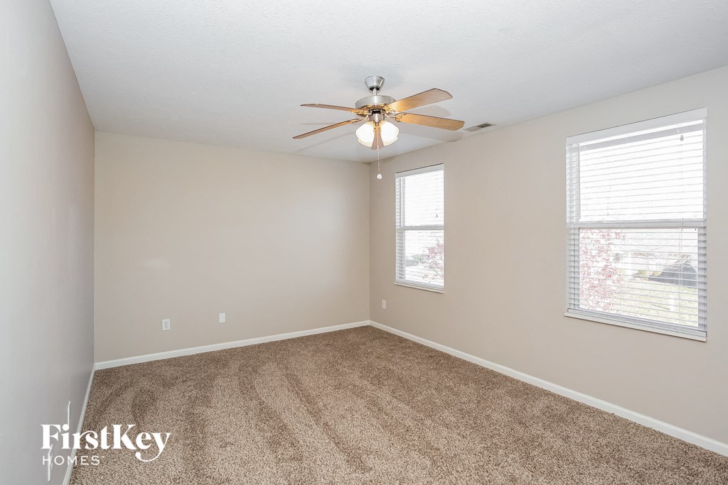 a bedroom with carpet and a ceiling fan and two windows