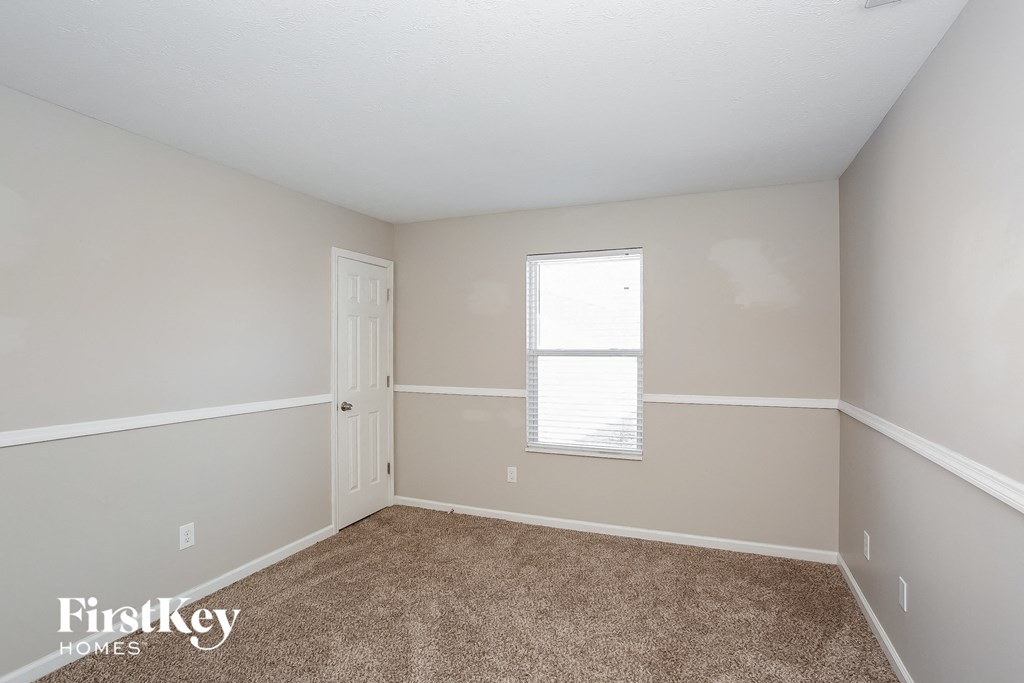 a bedroom with beige carpet and a white door