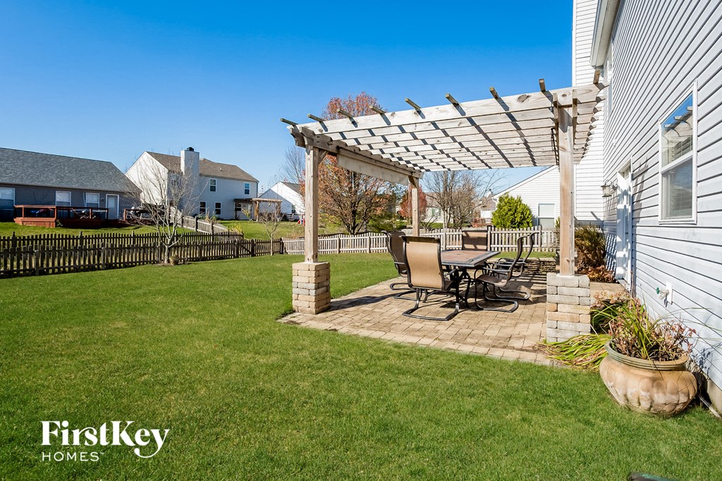 a backyard with a patio with a table and chairs and a pergola