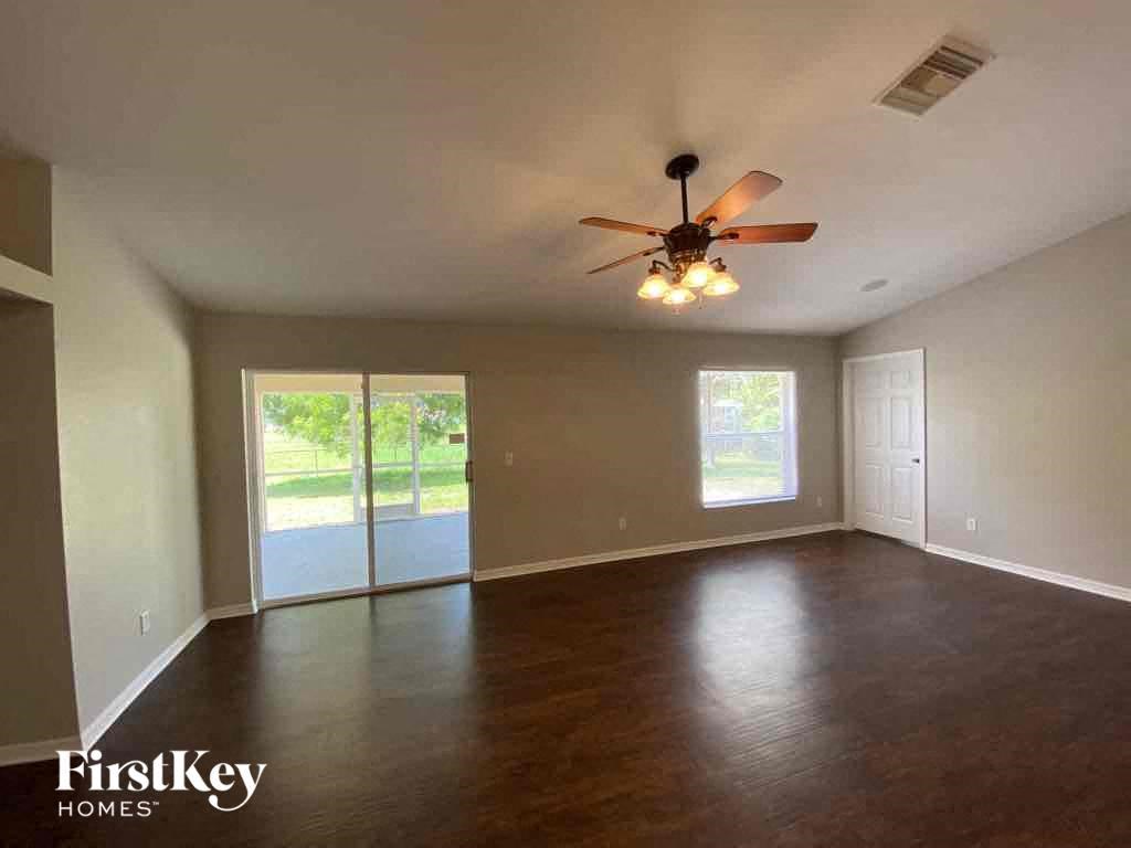 A spacious room with a ceiling fan and sliding glass doors leading to a patio.