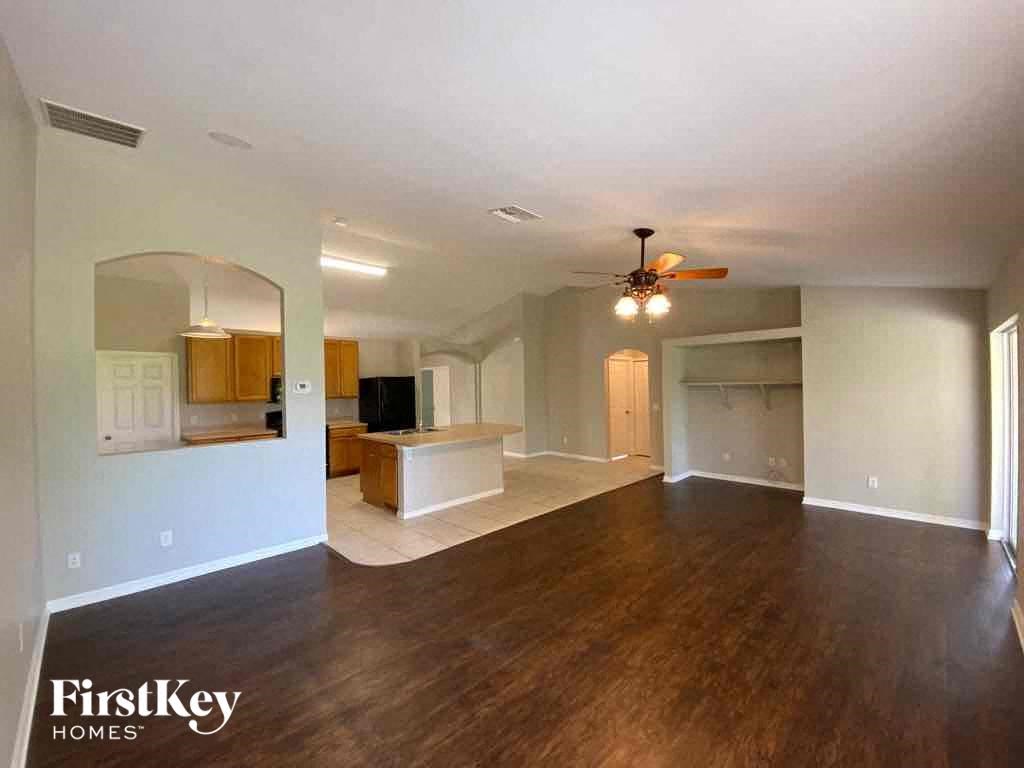 A spacious living room with wood flooring and a ceiling fan.