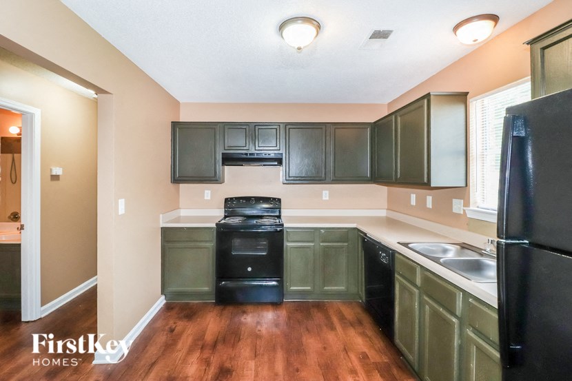an empty kitchen with black appliances and dark cabinets