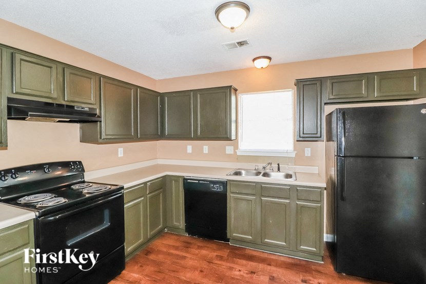 a kitchen with black appliances and green cabinets