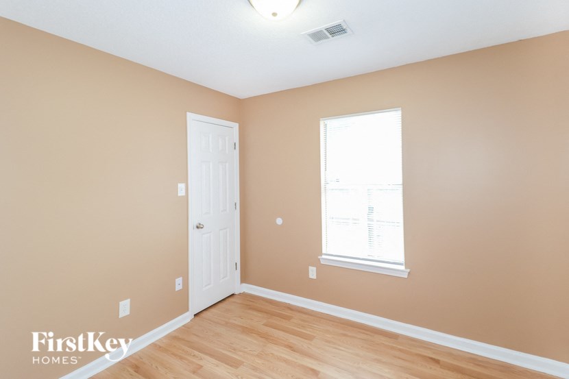 a bedroom with a door and a window and a wood floor