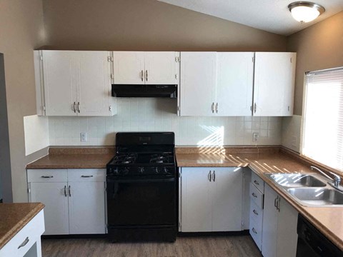 A kitchen with white cabinets and a black stove top oven.