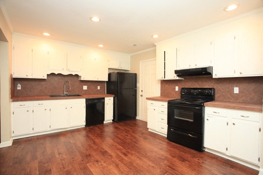 an empty kitchen with white cabinets and black appliances