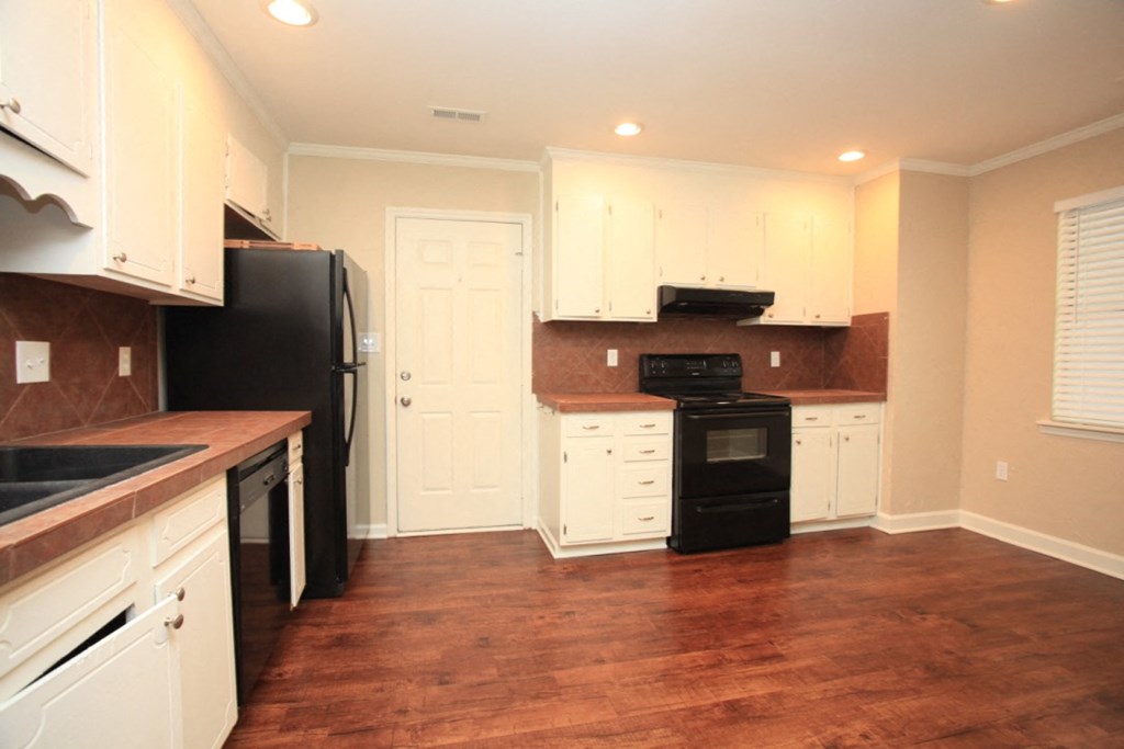 a kitchen with white cabinets and black appliances