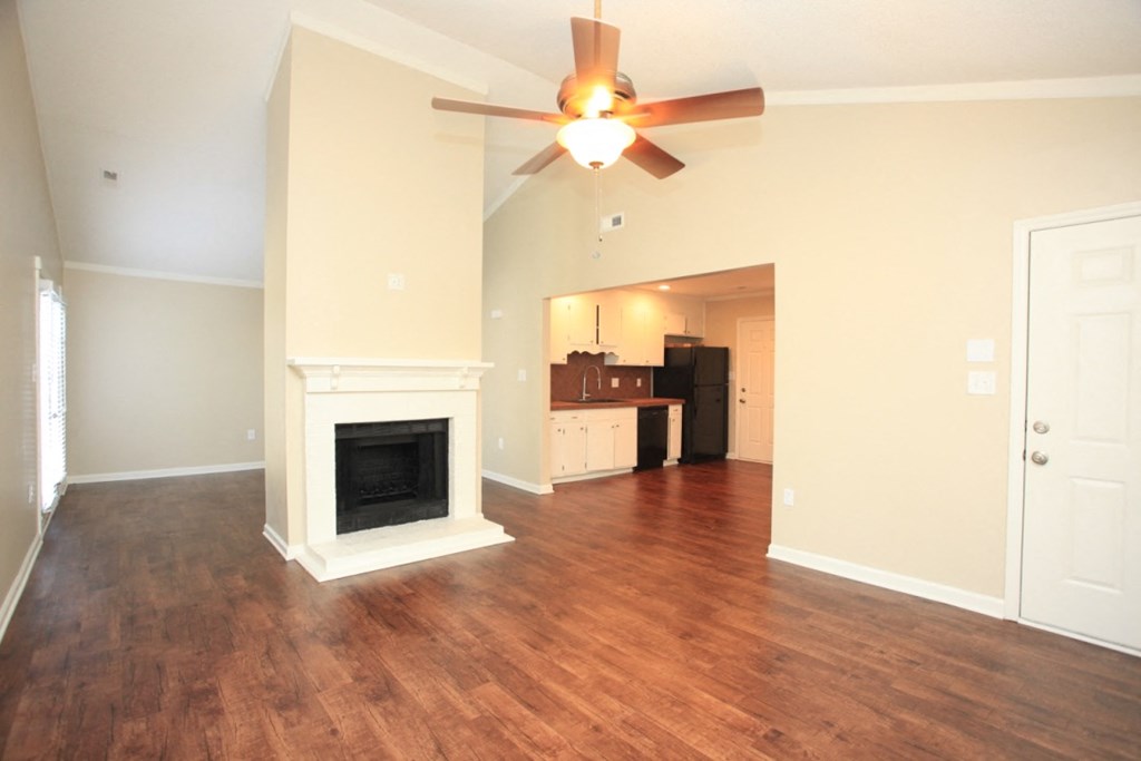 an empty living room with a fireplace and a ceiling fan