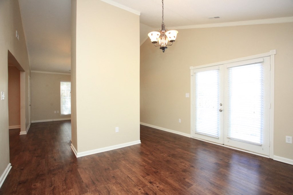 an empty living room with a hard wood floor and a chandelier