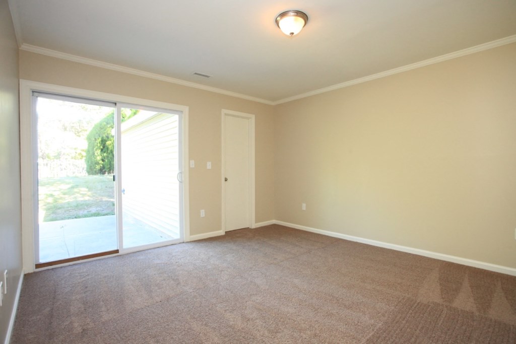 an empty living room with a sliding glass door to a patio