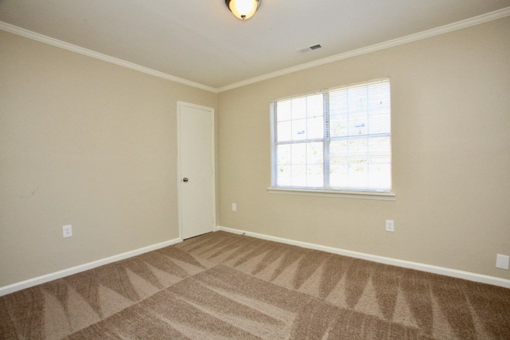 an empty living room with carpet and a window