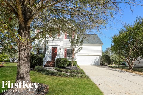 a white house with a red door and a tree in front of it
