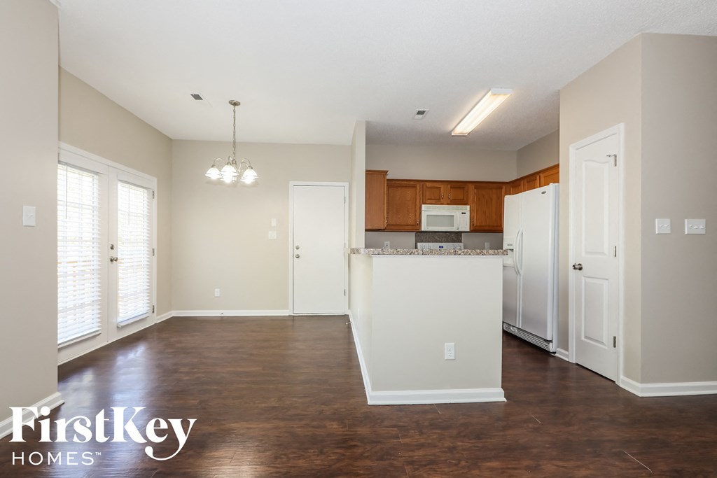 an empty kitchen with white appliances and wood flooring