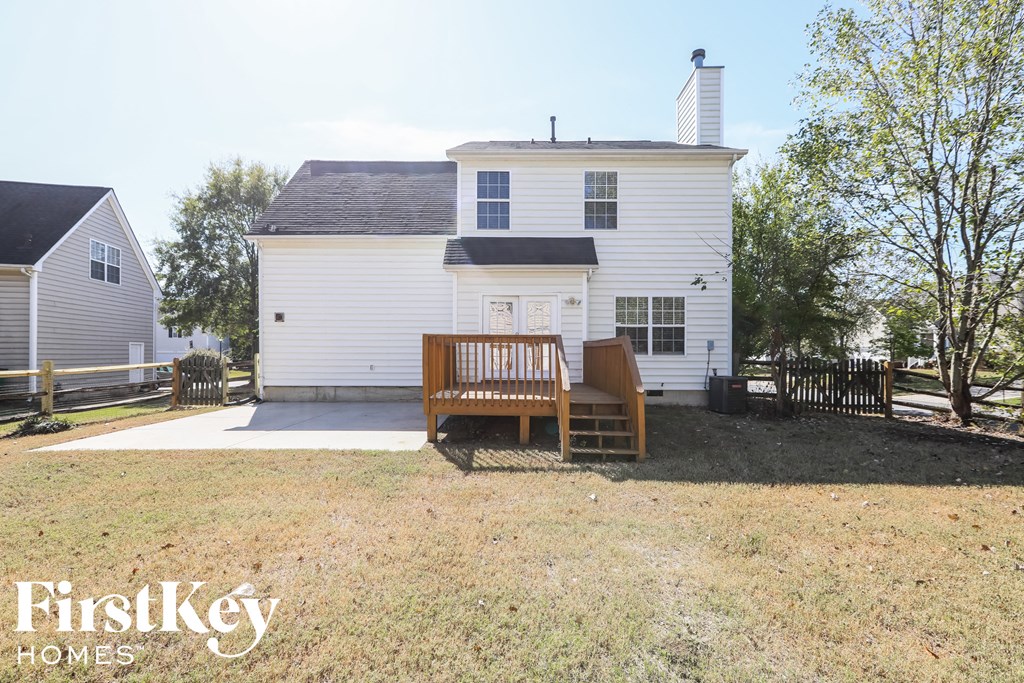 a backyard with a wooden bench in front of a white house