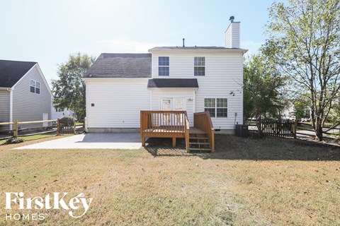a backyard with a wooden bench in front of a white house