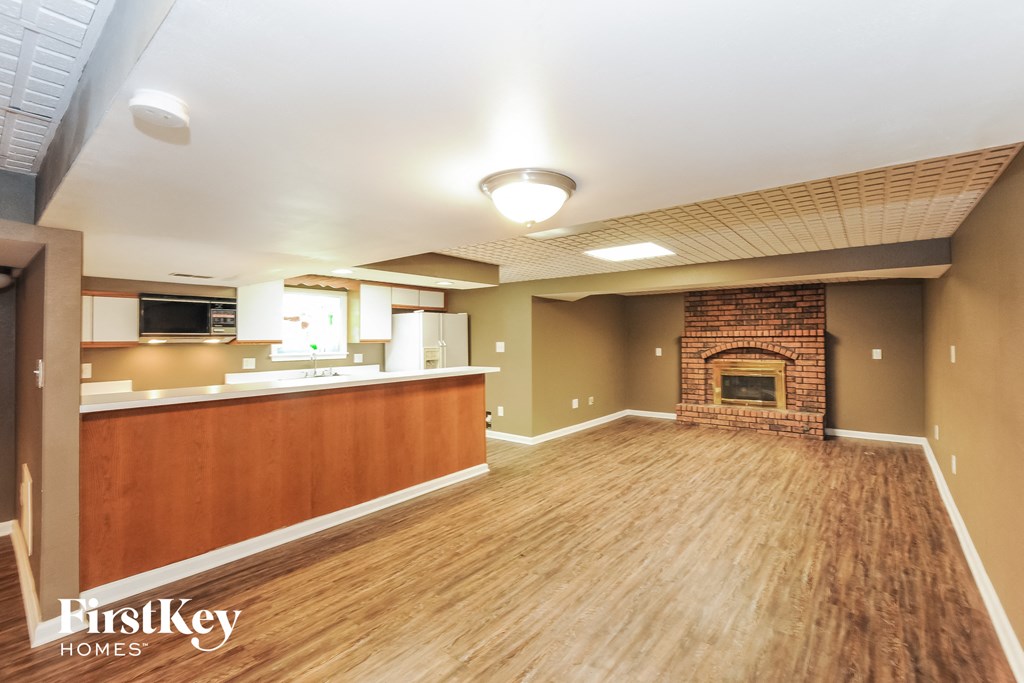 A spacious living room with wood flooring and a brick fireplace.
