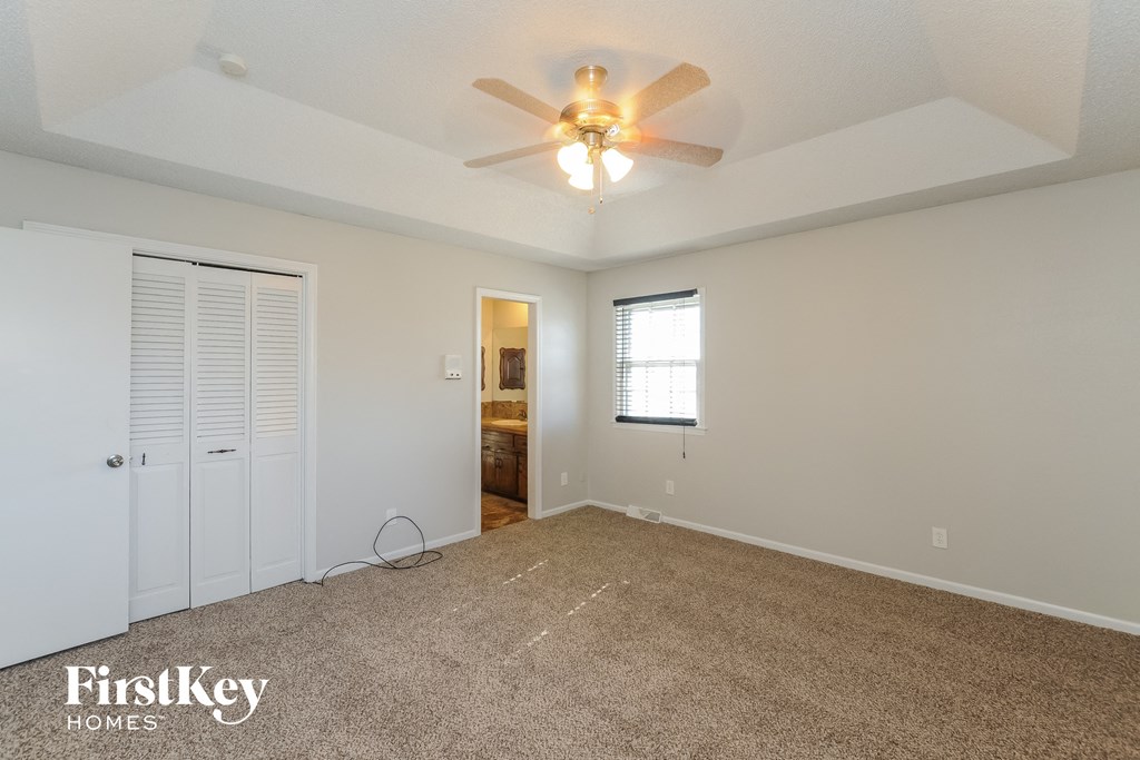 A spacious room with a ceiling fan and carpeted floor.