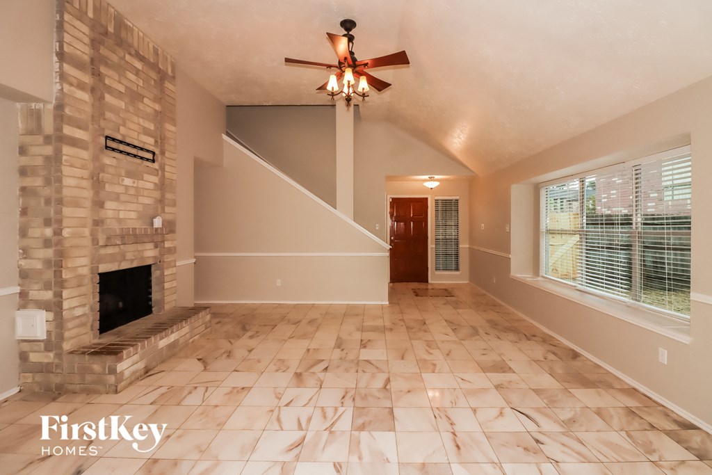 an empty living room with a fireplace and a ceiling fan