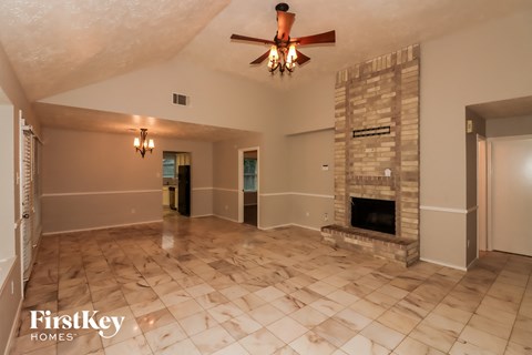 a large living room with a fireplace and a ceiling fan