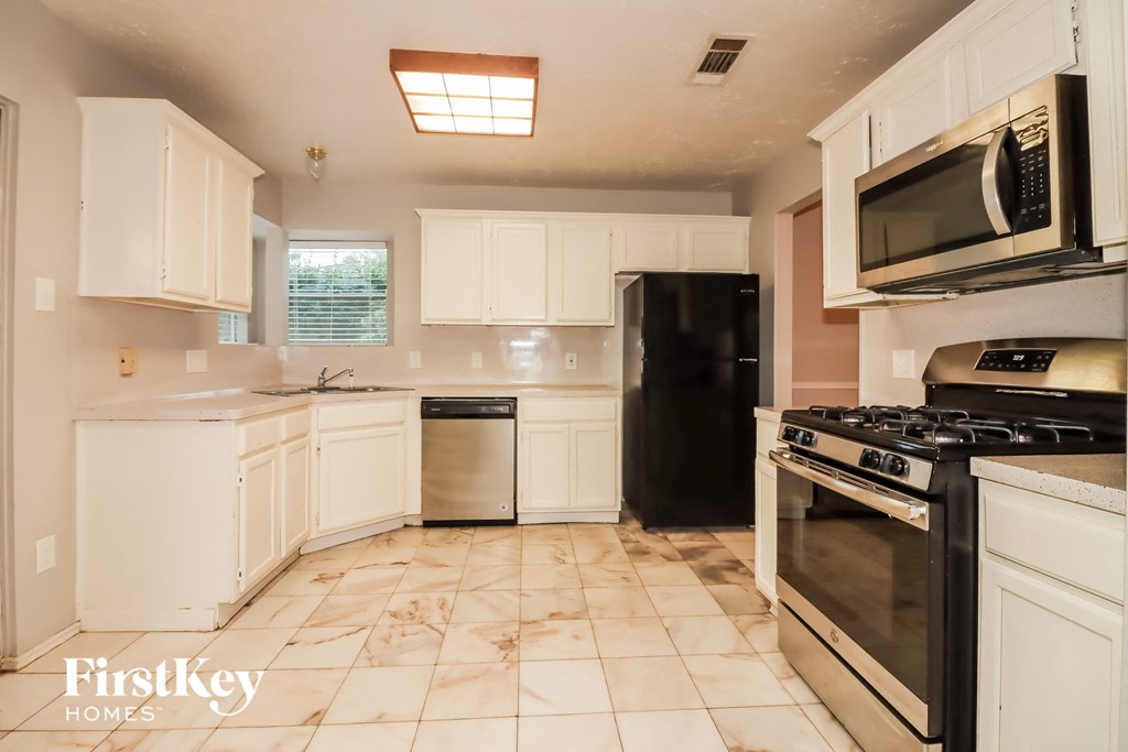 a kitchen with white cabinets and black appliances