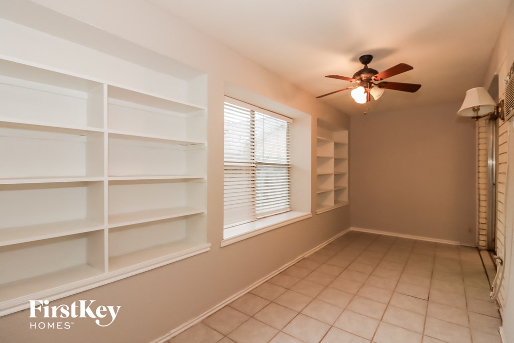 a walk in closet with white shelves and a ceiling fan