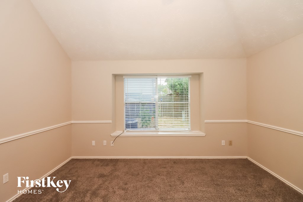 a bedroom with a window and a carpeted floor