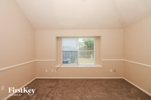 a bedroom with a window and a carpeted floor
