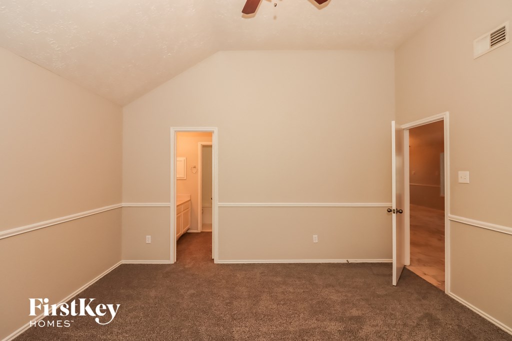 a bedroom with a carpeted floor and a door to a bathroom