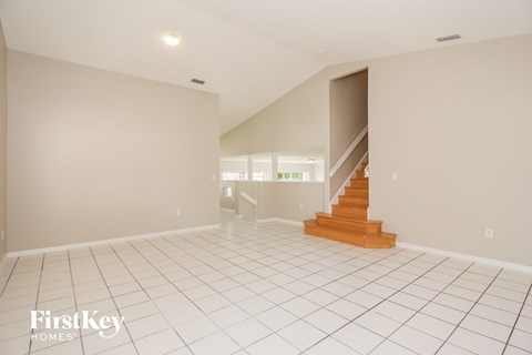 A spacious room with a staircase leading to another room.
