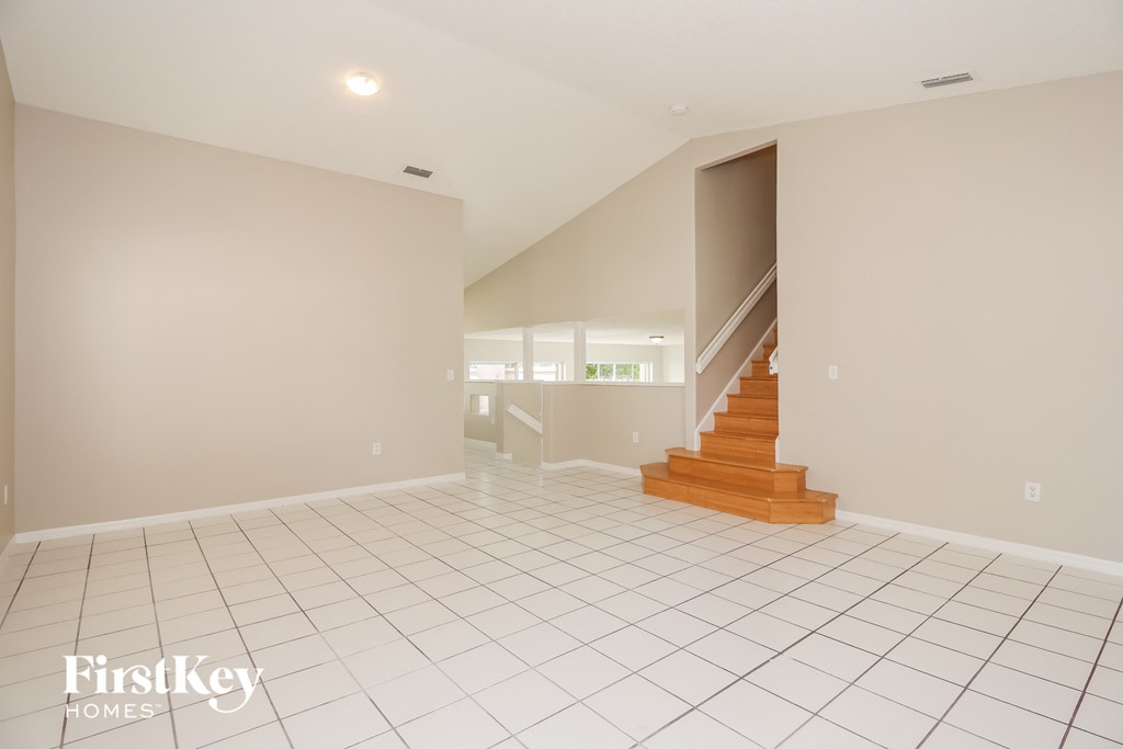 A spacious room with a staircase leading to another room.