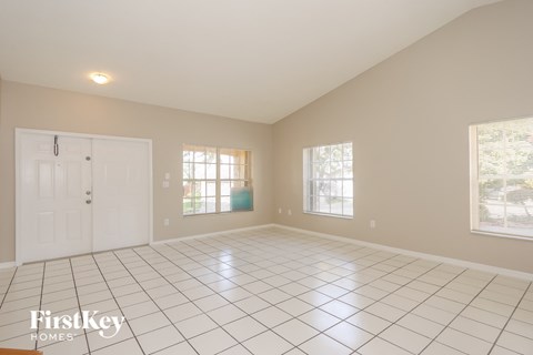 A spacious room with a white tile floor and a large window.