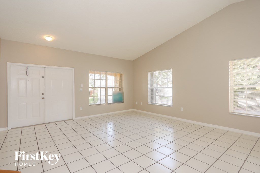 A spacious room with a white tile floor and a large window.