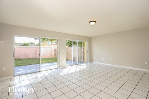 A large empty room with a tiled floor and sliding glass doors.
