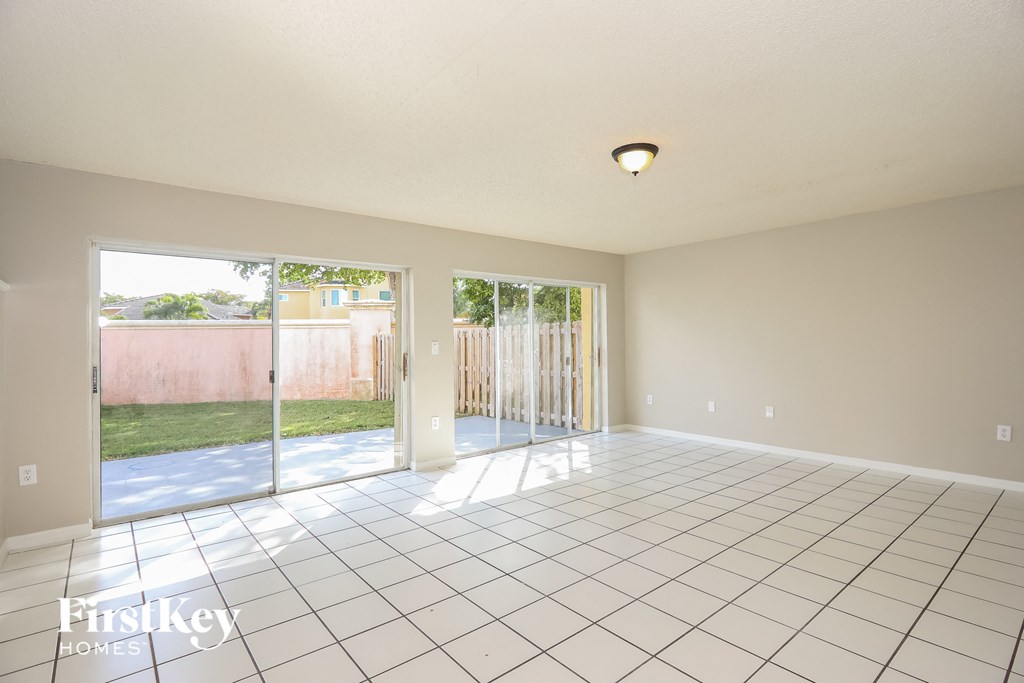 A large empty room with a tiled floor and sliding glass doors.