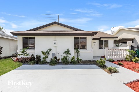 a white house with a driveway and a white picket fence